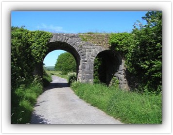 Double-arch rock-faced limestone railway bridge over road and over tributary of River Clashawley, built 1879
